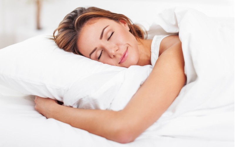 Žena spí na posteli s matrací a polštářem